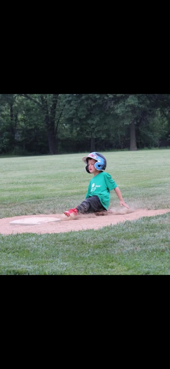 Young baseball player sliding toward a base